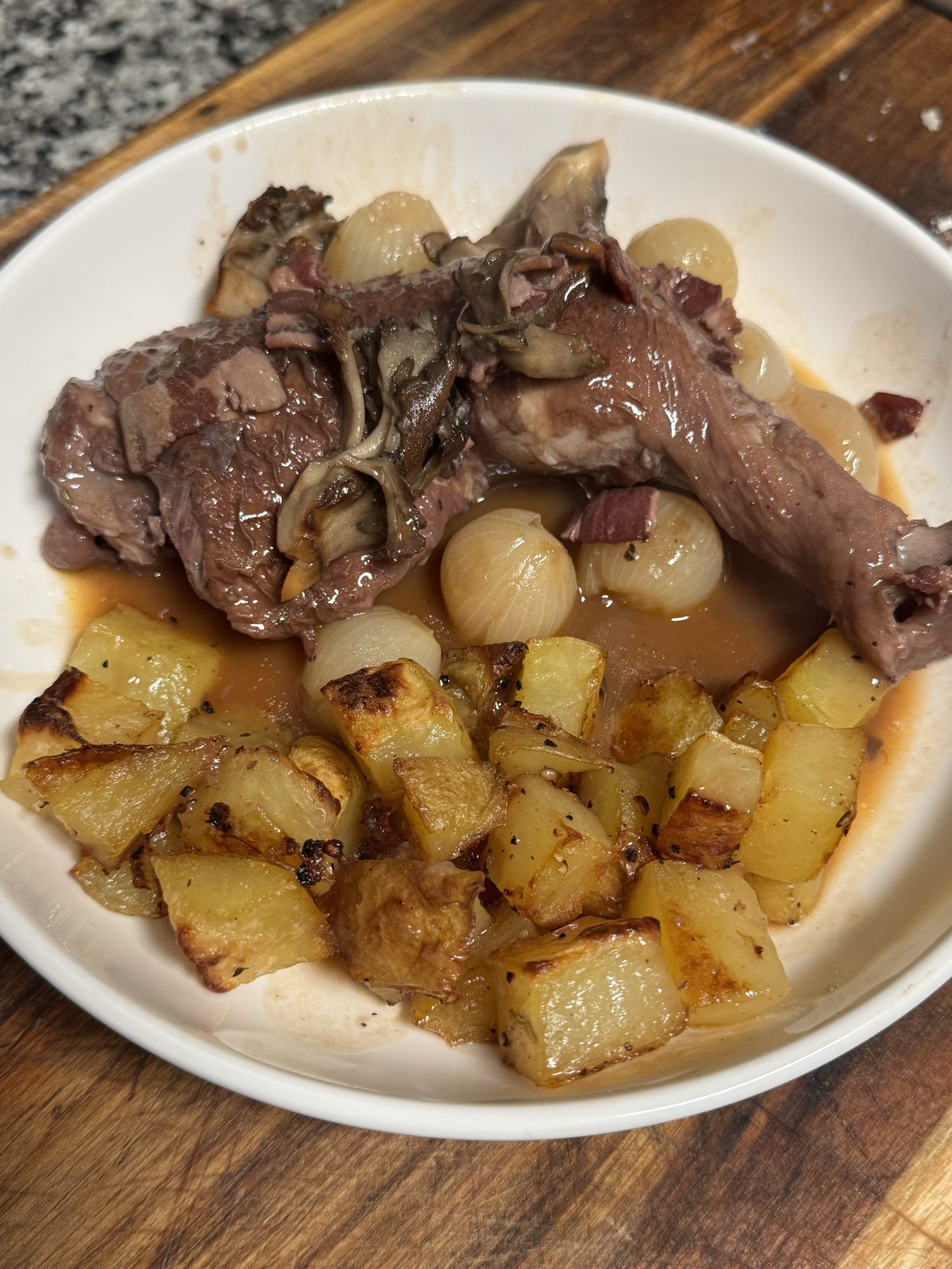 A rustic bowl of coq au vin, featuring tender chicken braised in red wine with mushrooms and onions, served in a deep dish.