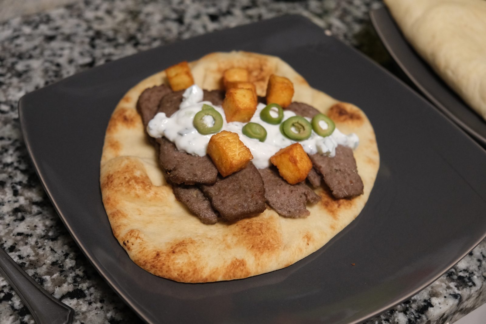Lamb gyro served with tzatziki, fried halloumi bites and olives on naan. 